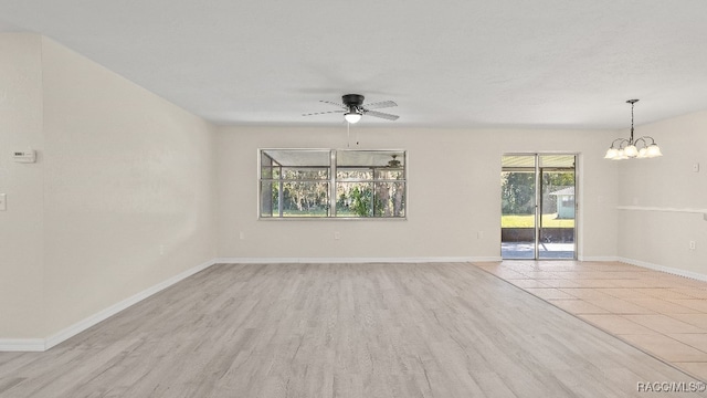 empty room with ceiling fan with notable chandelier and light hardwood / wood-style flooring