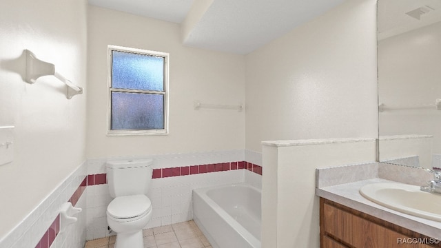 bathroom with tile patterned floors, a tub to relax in, toilet, vanity, and tile walls