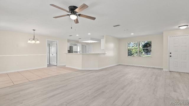 unfurnished living room featuring ceiling fan with notable chandelier and light hardwood / wood-style flooring