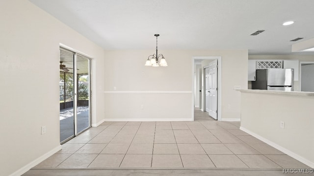 tiled empty room featuring a chandelier