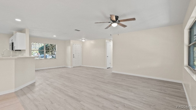 unfurnished living room with light hardwood / wood-style flooring, ceiling fan, and sink