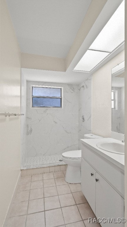 bathroom with tiled shower, vanity, tile patterned flooring, and toilet