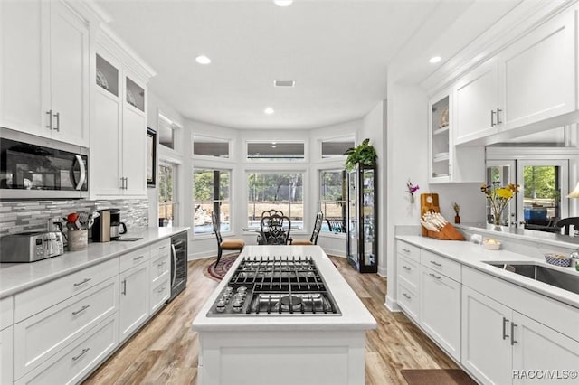 kitchen with white cabinetry, backsplash, light wood-type flooring, and stainless steel appliances