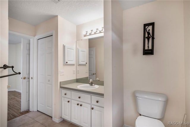 bathroom featuring toilet, vanity, tile patterned floors, and a textured ceiling