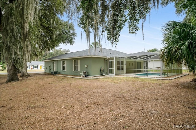 back of house with a lanai and central AC unit