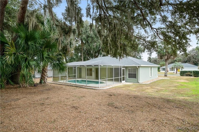 back of house with glass enclosure and a yard