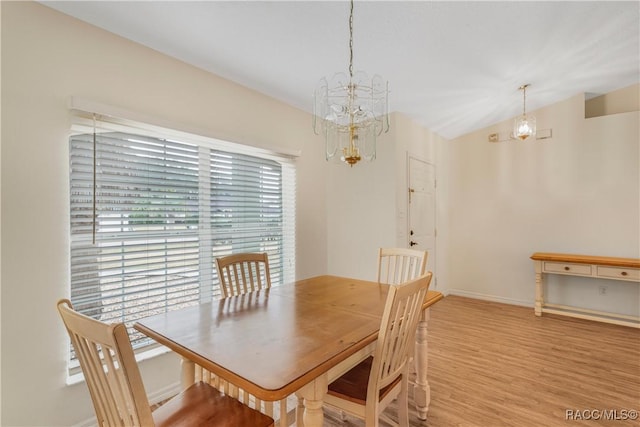 dining space with light hardwood / wood-style flooring and a chandelier