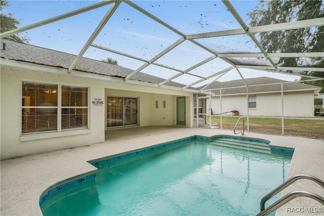 view of pool with glass enclosure and a patio area