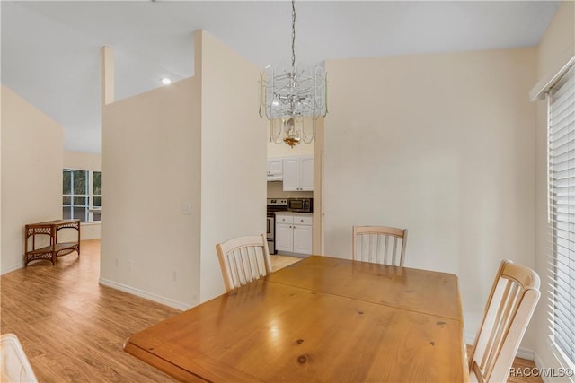 dining area featuring light wood-type flooring, an inviting chandelier, and lofted ceiling