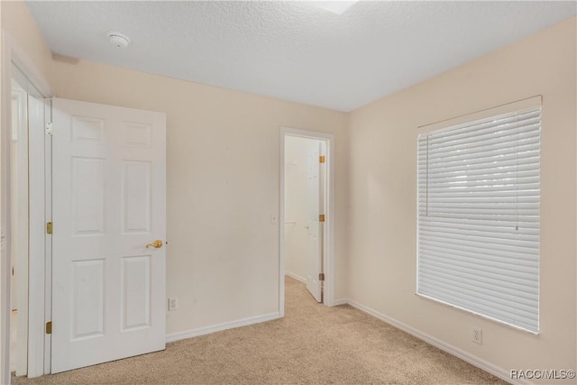 unfurnished bedroom featuring light carpet and a textured ceiling