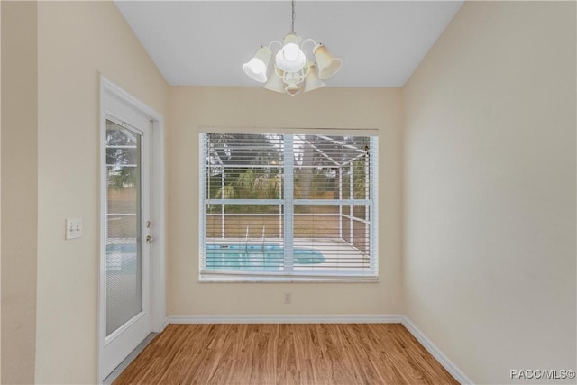 unfurnished dining area featuring plenty of natural light, a chandelier, and light hardwood / wood-style flooring