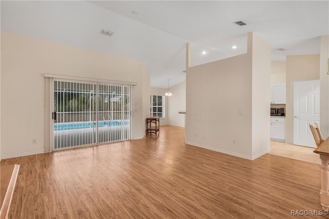 unfurnished living room with vaulted ceiling and light hardwood / wood-style floors