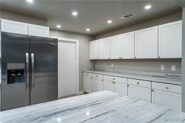 kitchen featuring light stone counters, white cabinetry, and stainless steel fridge with ice dispenser