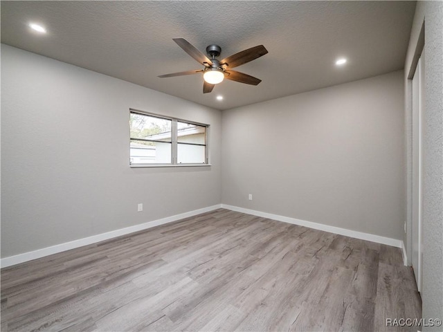 spare room featuring light hardwood / wood-style floors, a textured ceiling, and ceiling fan