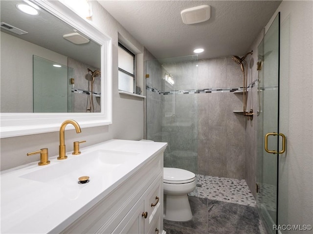 bathroom featuring toilet, a shower with door, a textured ceiling, and vanity