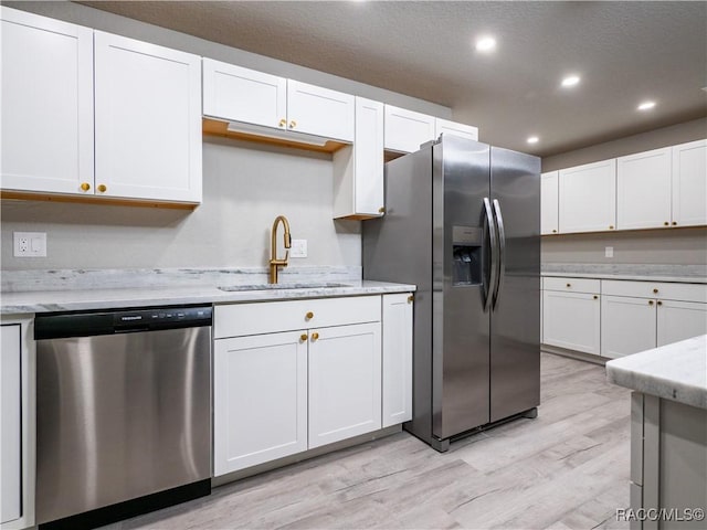 kitchen with sink, light stone counters, white cabinets, and appliances with stainless steel finishes