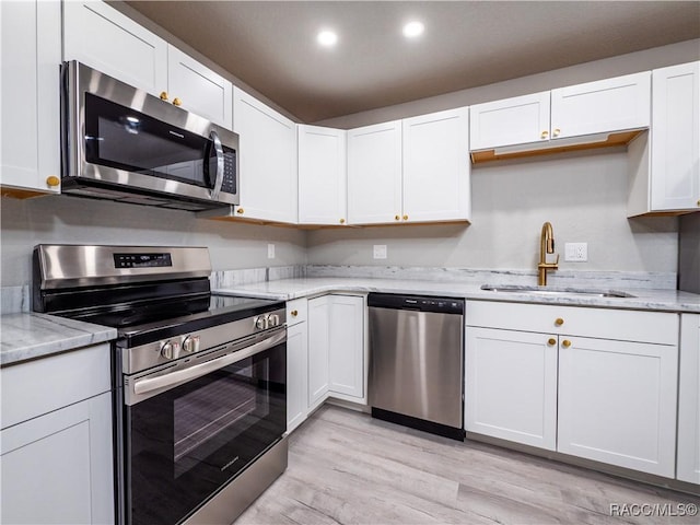 kitchen featuring sink, light hardwood / wood-style flooring, white cabinets, and appliances with stainless steel finishes