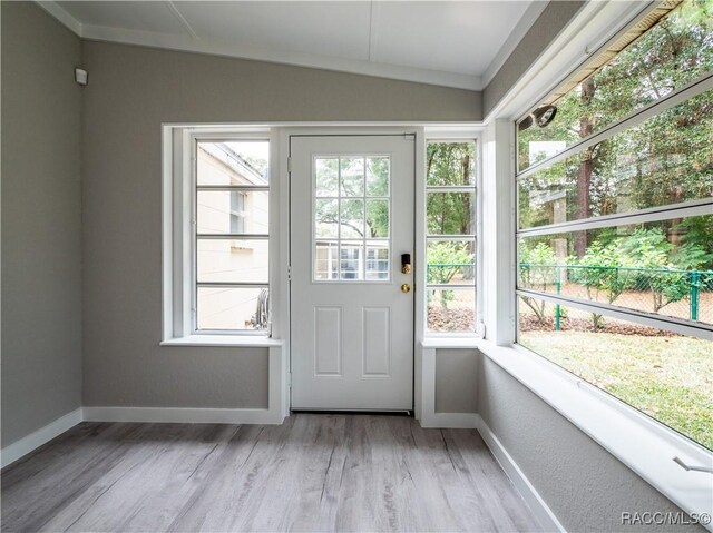 entryway with ornamental molding, a healthy amount of sunlight, lofted ceiling, and light hardwood / wood-style floors