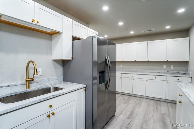 kitchen with sink, stainless steel refrigerator with ice dispenser, white cabinetry, and light wood-type flooring