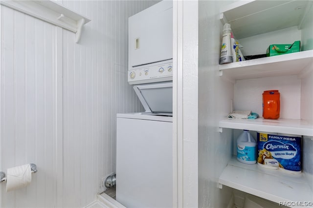 laundry area featuring wooden walls and stacked washer and clothes dryer