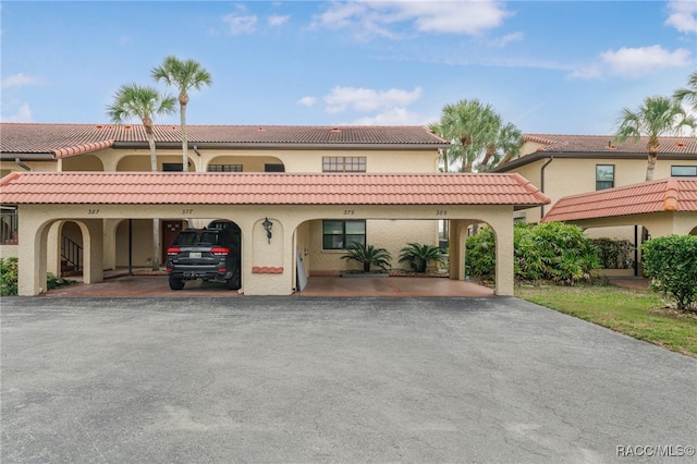 view of front of house featuring covered parking, stucco siding, and a tile roof