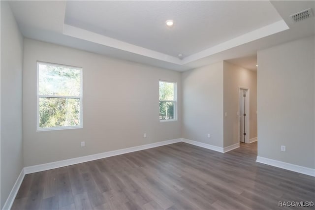 unfurnished room with a tray ceiling and dark hardwood / wood-style flooring