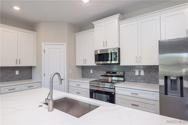 kitchen with stainless steel appliances, sink, decorative backsplash, and white cabinets