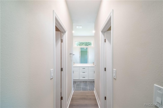 corridor with hardwood / wood-style floors and sink