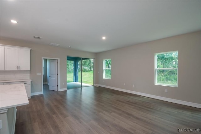 unfurnished living room with dark hardwood / wood-style floors and a healthy amount of sunlight