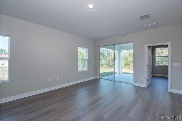 spare room with dark hardwood / wood-style floors and a textured ceiling