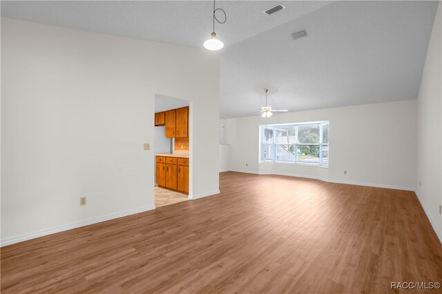 unfurnished living room with ceiling fan, high vaulted ceiling, light hardwood / wood-style floors, and a textured ceiling