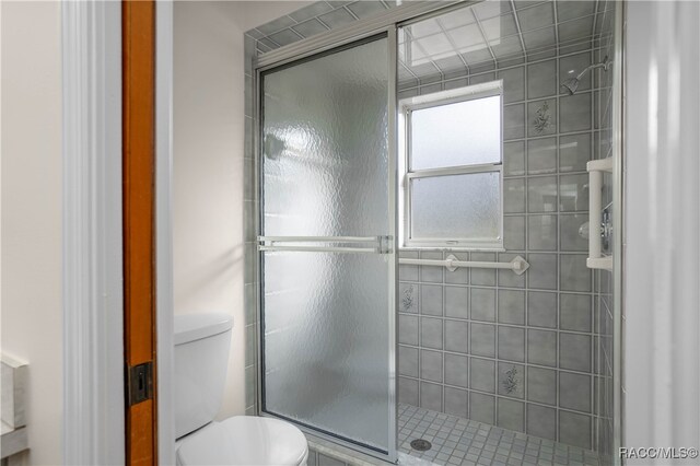 bathroom featuring toilet and an enclosed shower