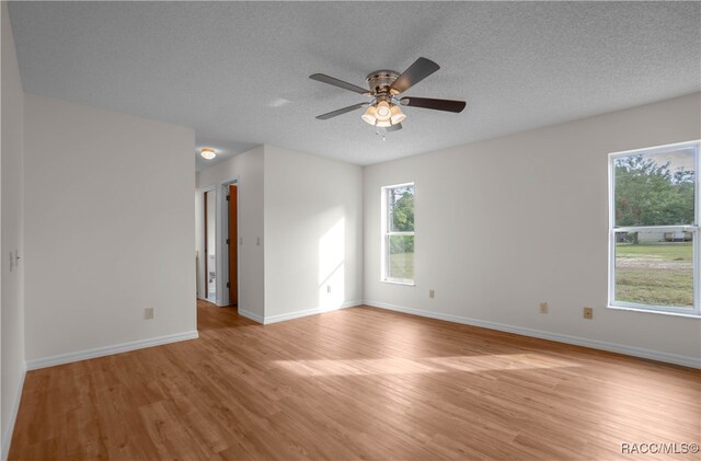 spare room with ceiling fan, light hardwood / wood-style flooring, and a textured ceiling