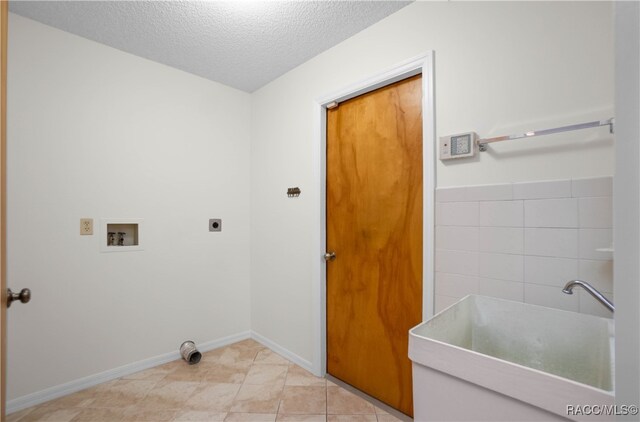 laundry room featuring electric dryer hookup, sink, hookup for a washing machine, a textured ceiling, and light tile patterned flooring