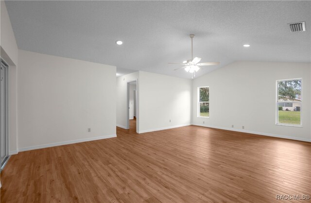 unfurnished living room with light hardwood / wood-style floors, vaulted ceiling, plenty of natural light, and ceiling fan