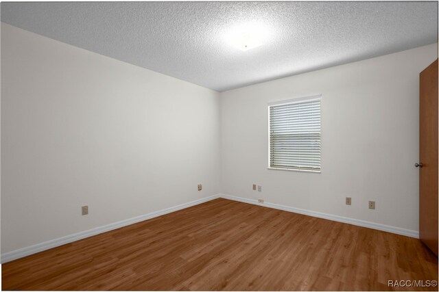 empty room featuring wood-type flooring and a textured ceiling