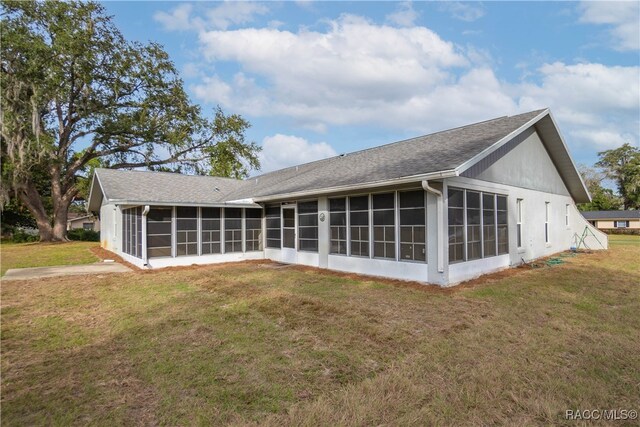 back of house featuring a lawn and a sunroom