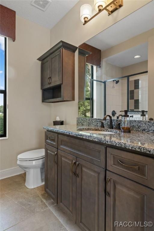 bathroom featuring vanity, toilet, and a tile shower