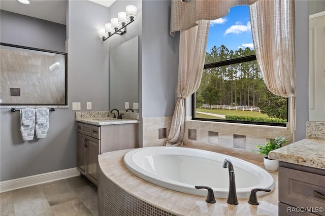 bathroom with vanity, tiled bath, and plenty of natural light