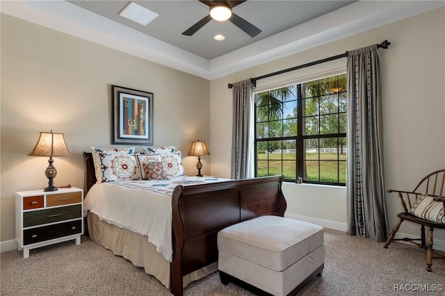 carpeted bedroom with a raised ceiling and ceiling fan