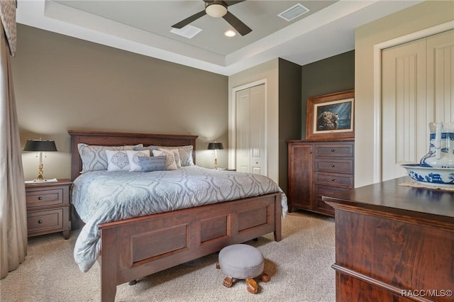 bedroom featuring light carpet, a raised ceiling, and ceiling fan