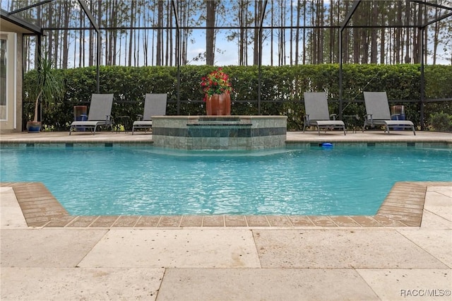 pool with glass enclosure, a patio, and a jacuzzi