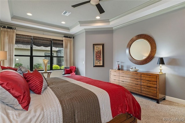 carpeted bedroom with a tray ceiling, ceiling fan, and crown molding