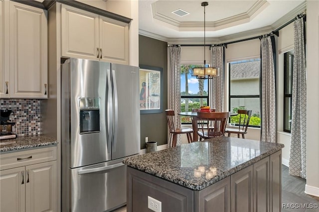 kitchen with decorative backsplash, stainless steel fridge, pendant lighting, and dark stone counters