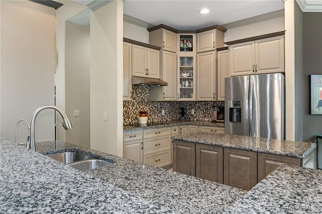 kitchen with stainless steel fridge with ice dispenser, backsplash, light stone counters, and crown molding