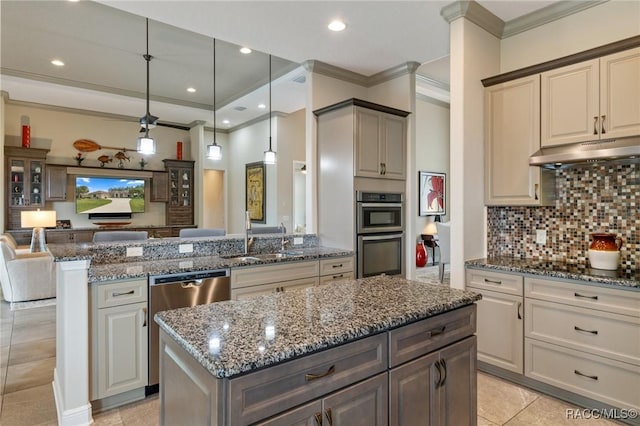 kitchen with a center island, sink, dark stone countertops, pendant lighting, and appliances with stainless steel finishes