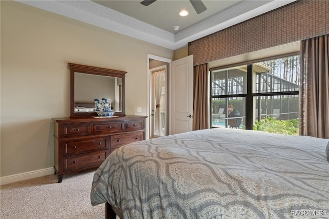 bedroom featuring light colored carpet, a raised ceiling, and ceiling fan