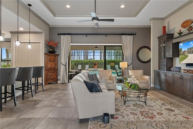 living room featuring a tray ceiling, ceiling fan, and crown molding