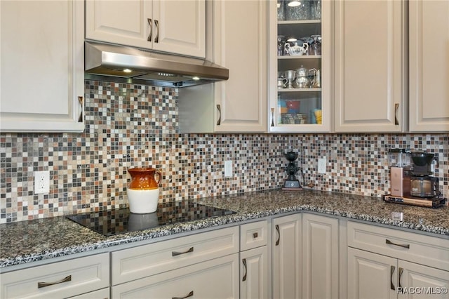 kitchen featuring black electric stovetop, decorative backsplash, and white cabinets