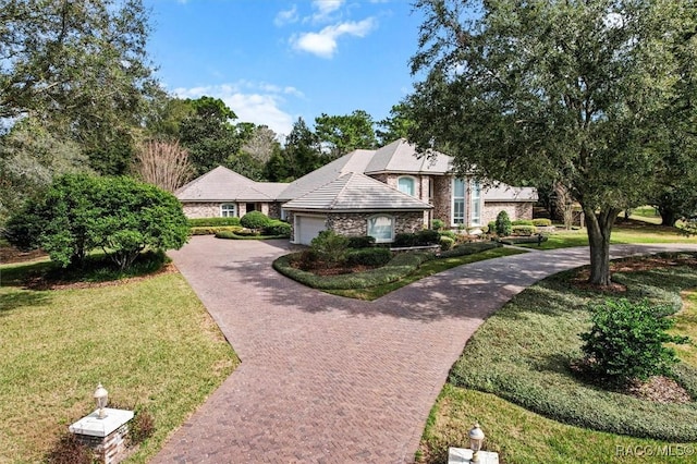 view of front of house with a garage, stone siding, a front lawn, and decorative driveway